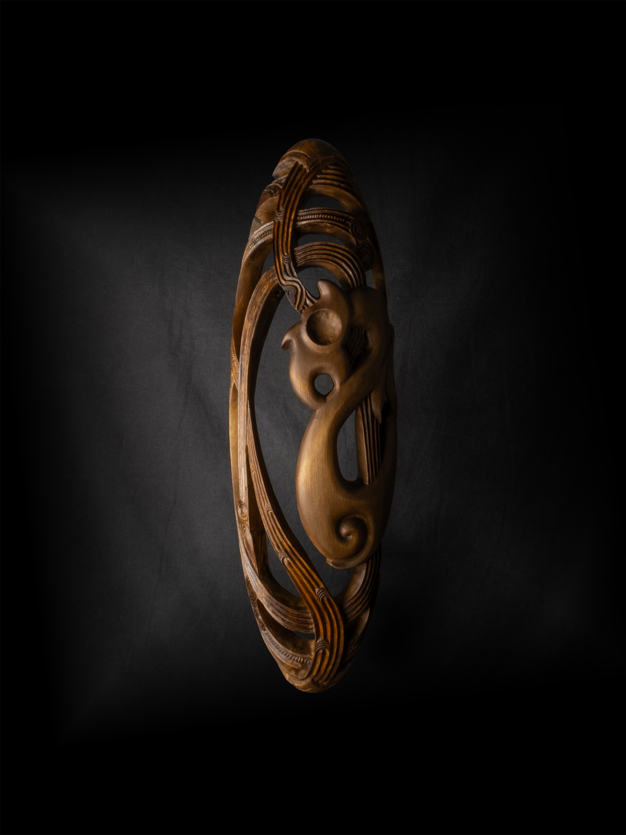 Artwork: Upoko Māro, an oval wooden carving with intricate details.
