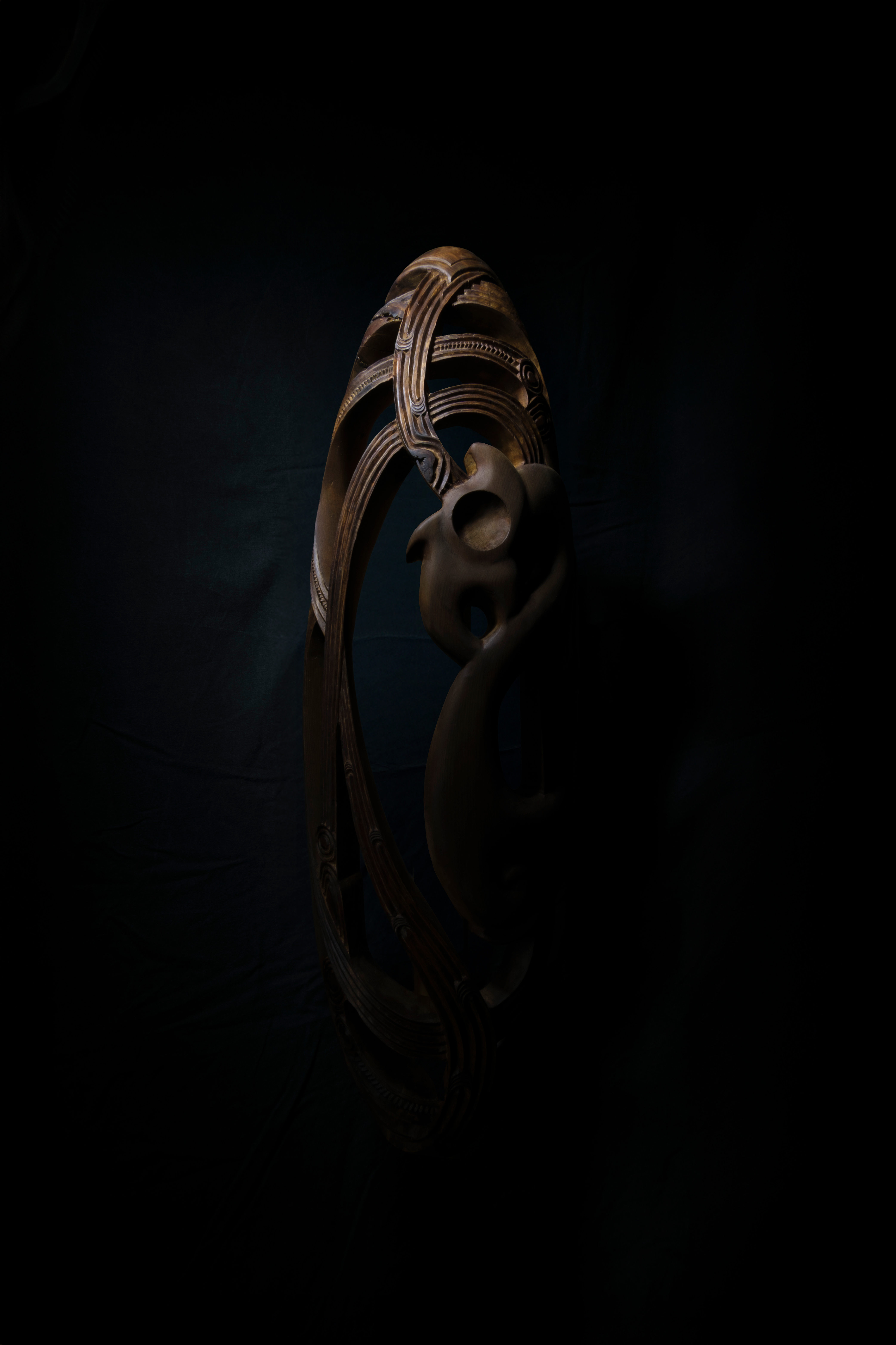 Artwork: Upoko Māro, an oval wooden carving with intricate details.